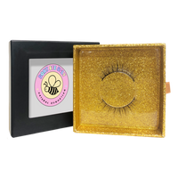 Thumbnail for Gold glittery box with false eyelashes and a visible brand logo on a white background