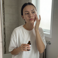 Thumbnail for Woman applying skincare serum in front of a mirror